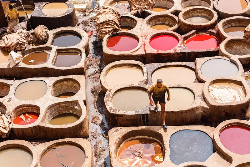 A 5 Days Tour from Marrakech to Fes nomadic Berber family sharing traditional mint tea with guests inside a woven goat-hair tent or mountain cave